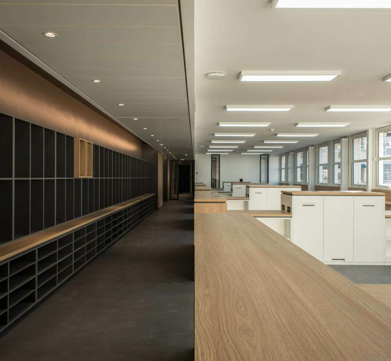 Vue en enfilade entre mur de casiers et plateau de bureaux éclairé, SAV Horlogerie Chanel ; conception lumière Ponctuelle