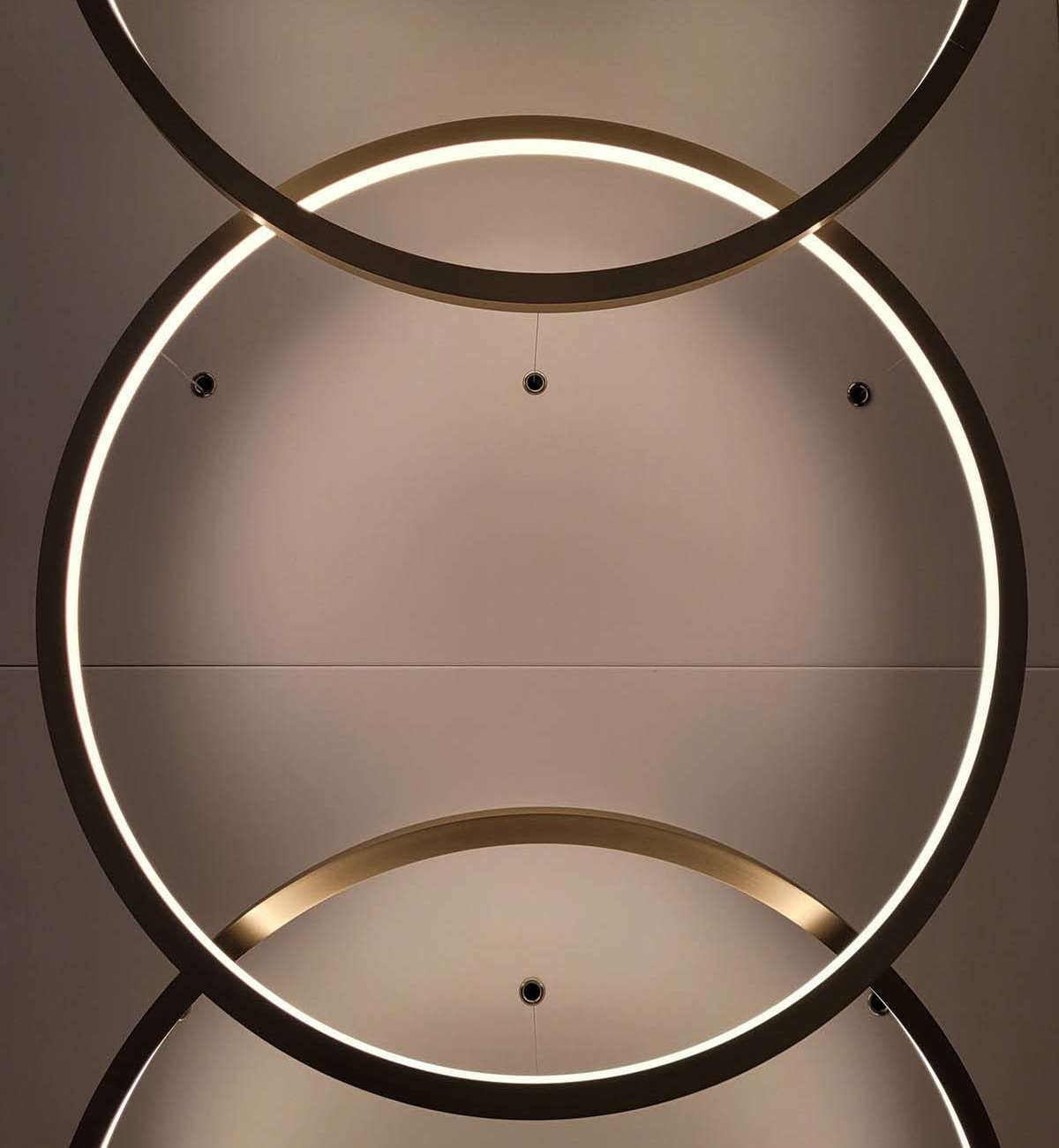 Détail de luminaires circulaires entrelacés au plafond, conception lumière bureaux Paris Ponctuelle
