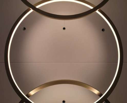Détail de luminaires circulaires entrelacés au plafond, conception lumière bureaux Paris Ponctuelle