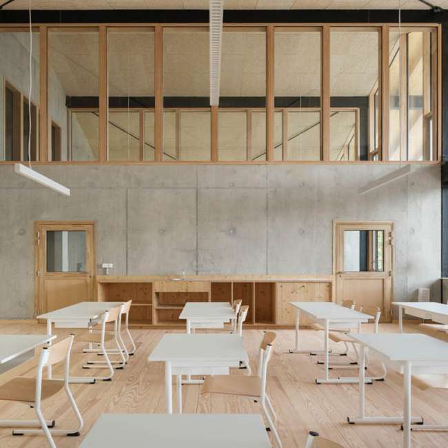 Salle de classe à la charpente bois apparente, suspensions lumineuses linéaires, conception lumière Ponctuelle