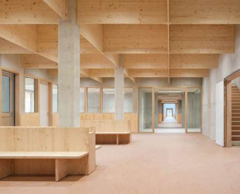 Espace commun sous charpente bois lamellé-collé avec bancs intégrés, conception lumière Ponctuelle
