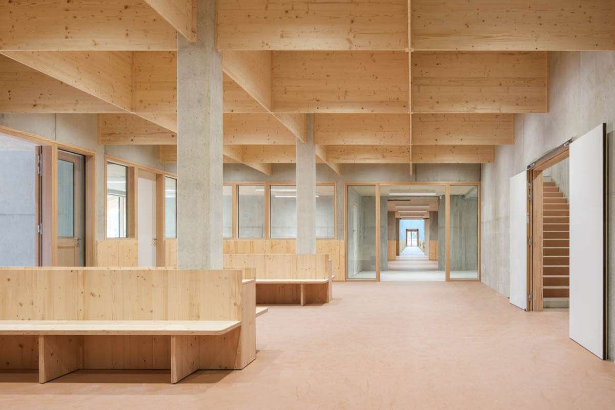 Espace commun sous charpente bois lamellé-collé avec bancs intégrés, conception lumière Ponctuelle