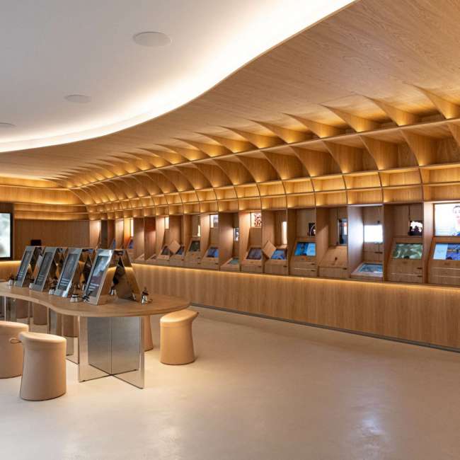 Galerie courbe en bois retraçant l'histoire de la marque, éclairage indirect par Ponctuelle pour L'Oréal Le Visionnaire