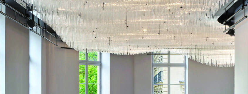 Hall d'accueil sous un lustre monumental en tubes de verre suspendus, mise en lumière L'Oréal Le Visionnaire